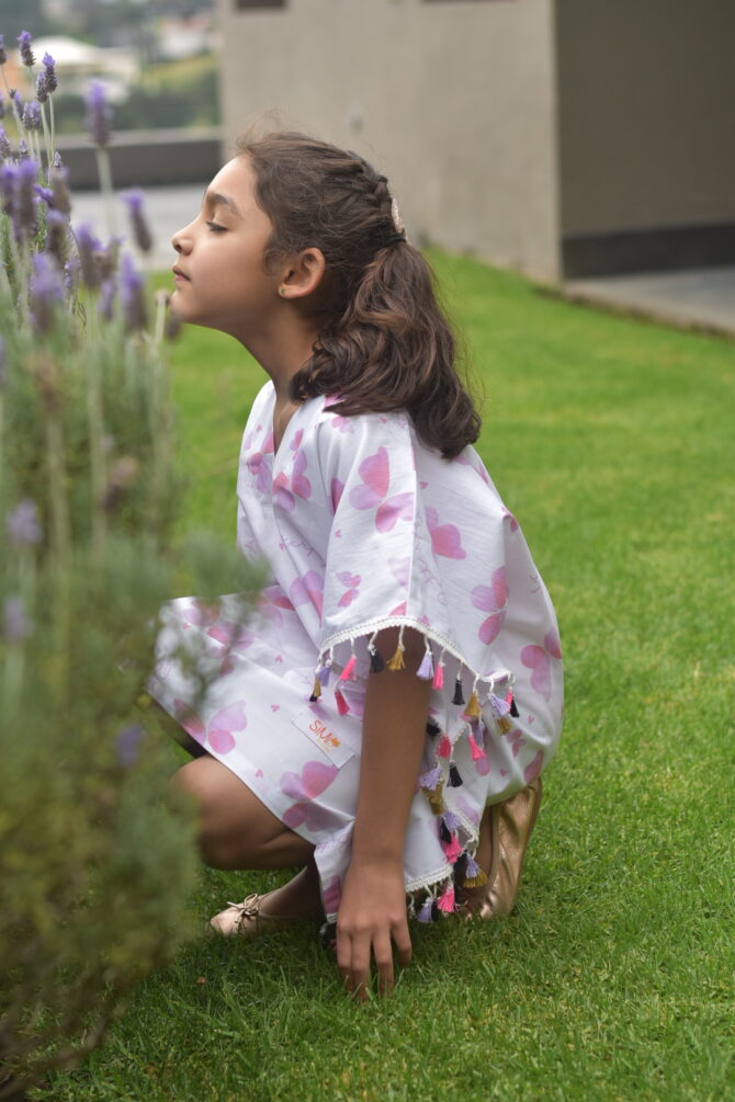 girl in kaftan smelling flowers