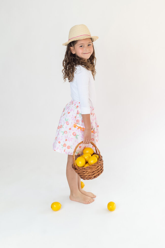 Girl in skirt holding a basket with lemons